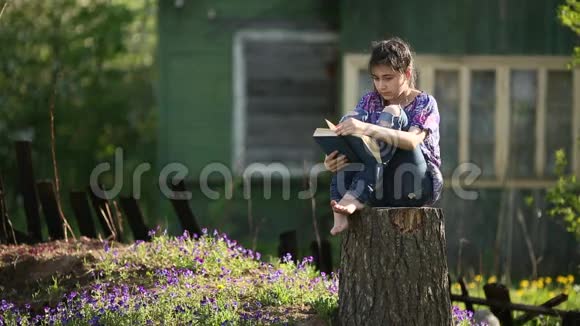 少女坐在院子里的树桩上看书视频的预览图
