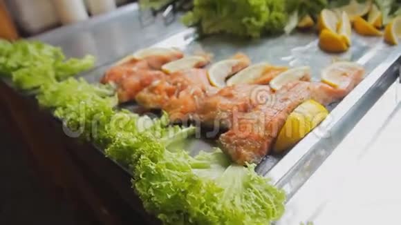 烤红鲑鱼加沙拉桌上放着青菜和柠檬的煮熟的鱼片美食节上烤鱼视频的预览图