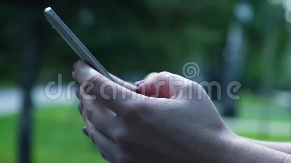 女性手特写使用智能手机通过触摸屏上的信息电话屏幕显示视频的预览图