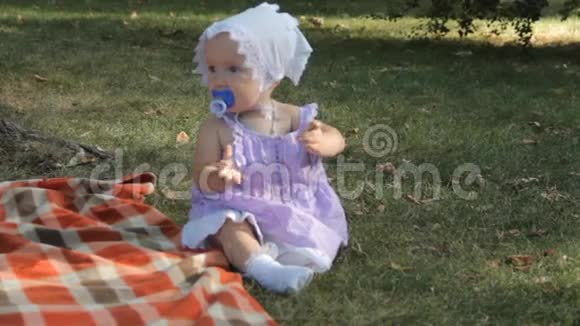 一个小女孩坐在草地上的毯子上视频的预览图