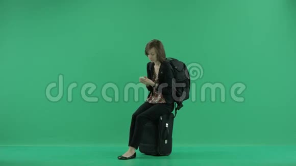 女游客坐在手提箱上等待视频的预览图