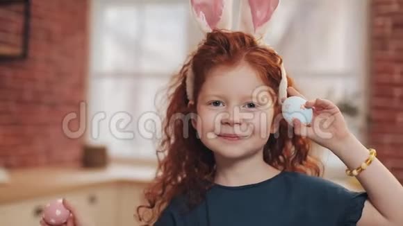 欢快的红头小女孩的肖像带着兔子耳朵厨房背景上有一个复活节彩蛋她是视频的预览图