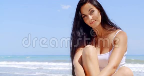 在海滩上坐在阳光下的布鲁内特女士视频的预览图