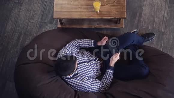 躺在椅子上男人喝着果汁看着药片视频的预览图