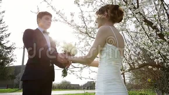 新郎给新娘一束花树背景的婚礼花束视频的预览图