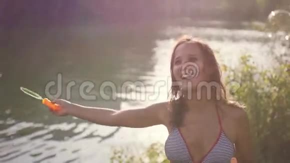 美丽的年轻快乐的黑发女人在阳光明媚的夏天在海滩上吹泡泡1920x1080视频的预览图