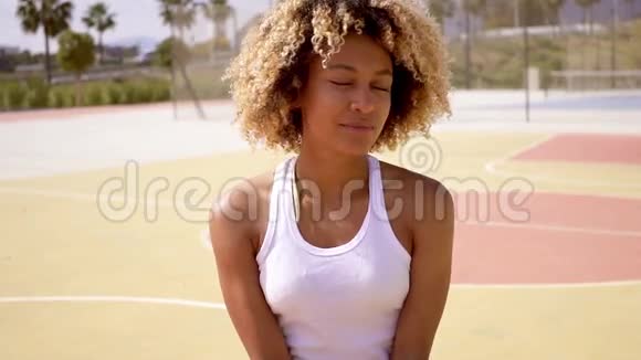 漂亮年轻的女运动员坐在篮球上视频的预览图