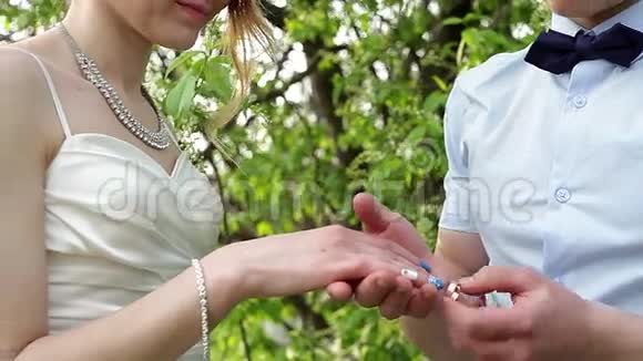 新郎在春天的花园里穿新娘结婚戒指视频的预览图