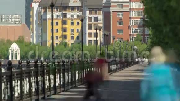 伊希姆河上人们漫步在滨水的时空建筑物房屋广场和树木上阳光明媚的一天阿斯塔纳视频的预览图