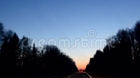 在日出前的森林道路上行驶的汽车视频的预览图