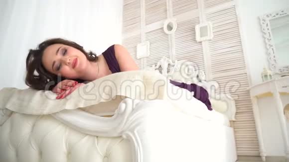 一个穿着紫色裙子的漂亮女孩躺在白色的床上做梦视频的预览图