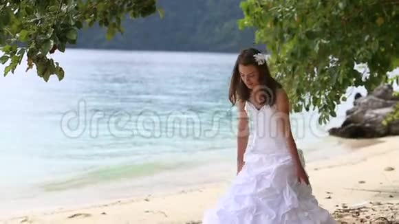 长发新娘坐在沙滩上站在海边和岛上视频的预览图
