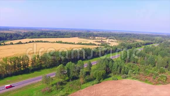 无人机在成熟的黑麦地之间飞过高速公路视频的预览图