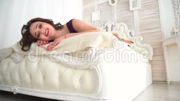 穿紫色衣服的年轻女子躺在白色的床上做梦视频的预览图