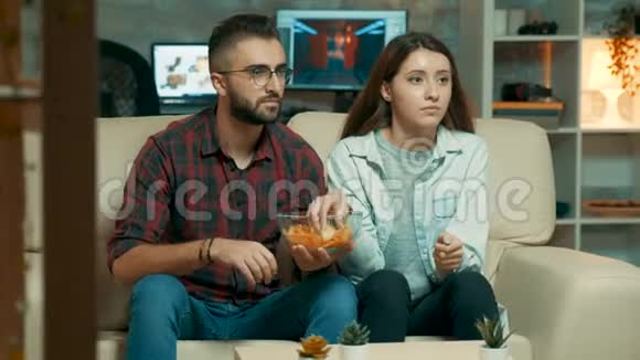 集中的白种人年轻夫妇一边看电视视频的预览图