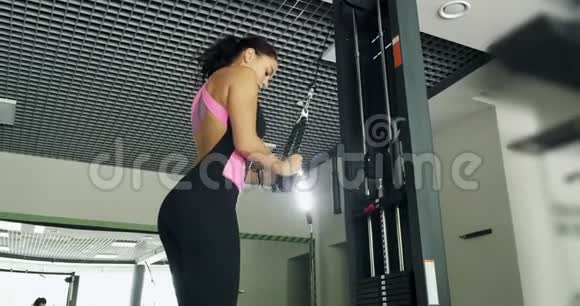 在体育俱乐部运动模拟器上训练肌肉的强壮漂亮的女人运动女性在健身机上做运动视频的预览图