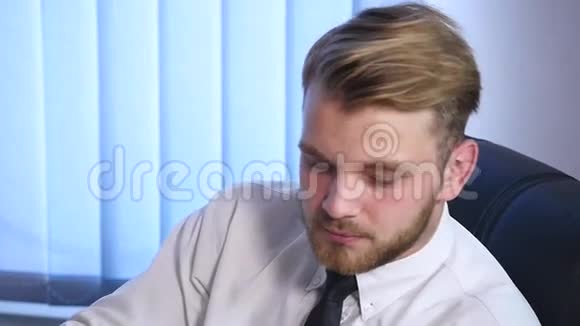 坐在办公室用电脑工作的大胡子年轻人的画像视频的预览图