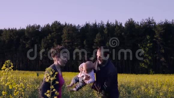 妈妈爸爸和儿子在油菜田里跳舞玩耍视频的预览图