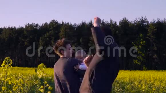 妈妈爸爸和儿子在油菜田里跳舞玩耍视频的预览图