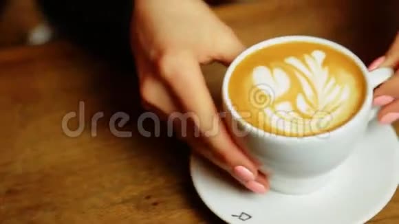 女人的手把一杯白色的咖啡放在桌子上然后放一个勺子视频的预览图