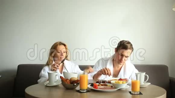 年轻夫妇在酒店房间的沙发上吃早餐视频的预览图