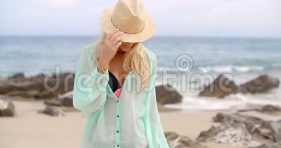 沙滩上戴太阳帽的金发女子肖像视频的预览图