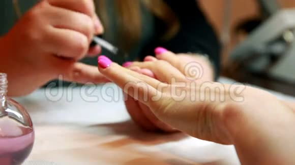 指甲技师把上衣涂在顾客的粉红色指甲上视频的预览图