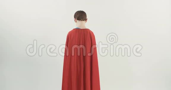穿着超级英雄斗篷的小男孩站在白色工作室背景上视频的预览图