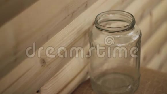 佩妮在木制背景下掉进一个透明的罐子里视频的预览图