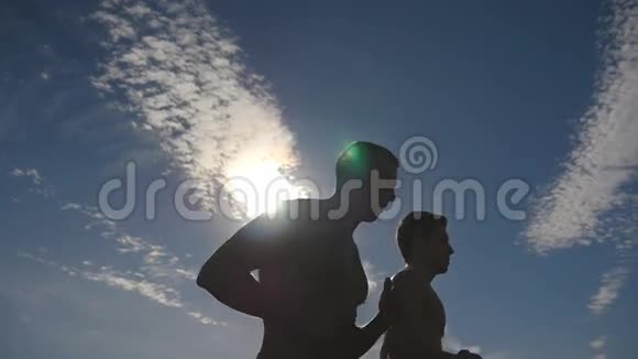 日落时分在乡下慢跑的男人剪影两名男子慢跑训练马拉松跑运动运动员视频的预览图