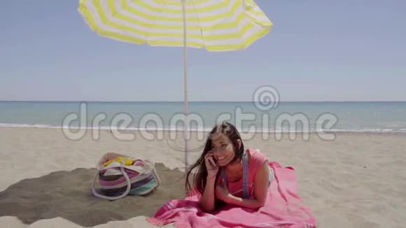 打电话的女人在海滩打伞视频的预览图