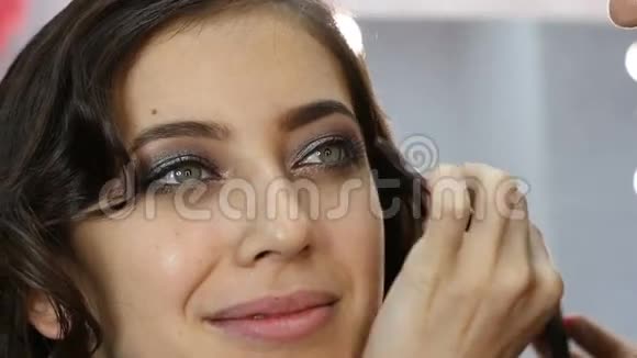 女性美女化妆师在年轻女性的眉毛上应用刷子化妆品视频的预览图