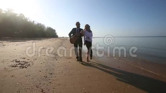 吉他手的演奏和金发女孩在沙滩上跳舞视频的预览图