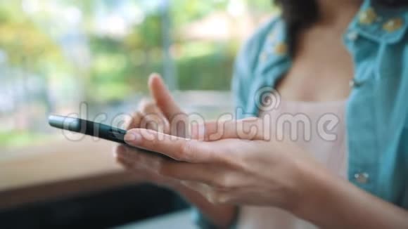 快乐的亚洲年轻女人坐在咖啡馆里用智能手机聊天阅读和发短信妇女生活方式概念视频的预览图