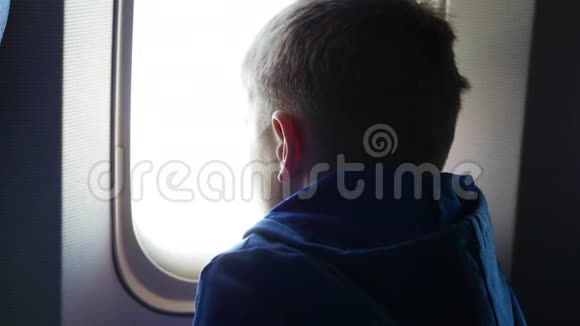 阳光明媚的一天一个孩子望着窗外的飞机视频的预览图