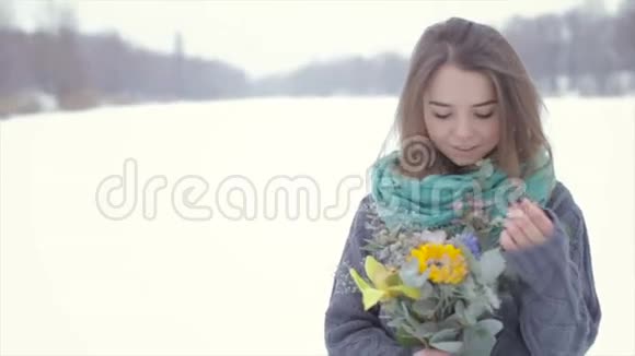 爱上一个穿灰色毛衣的女孩在冰冻的湖面上放着一束花视频的预览图
