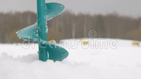为制冰钻一个洞水通过洞口浇灌冬天靠近森林的湖视频的预览图