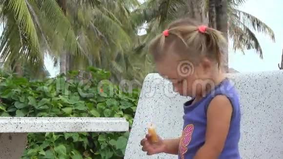 女孩吃面包坐在长凳上视频的预览图