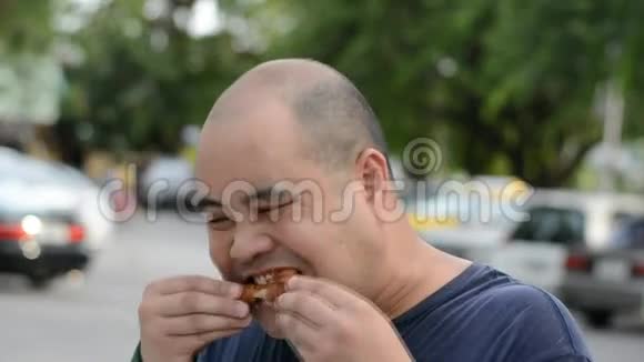 一个肥胖的亚洲秃头泰国男人贪婪地咬着吃炸鸡鸡腿饿得满脸都是冷汗视频的预览图