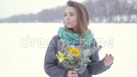 爱上一个穿灰色毛衣的女孩在冰冻的湖面上放着一束花视频的预览图