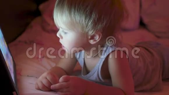傍晚时分一个小男孩在平板上看动画片视频的预览图