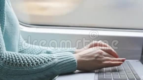 年轻女孩坐火车用笔记本在铁路上女性手按键盘打字视频的预览图