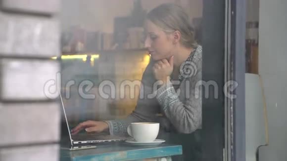 在咖啡馆里用笔记本电脑工作的年轻女子视频的预览图