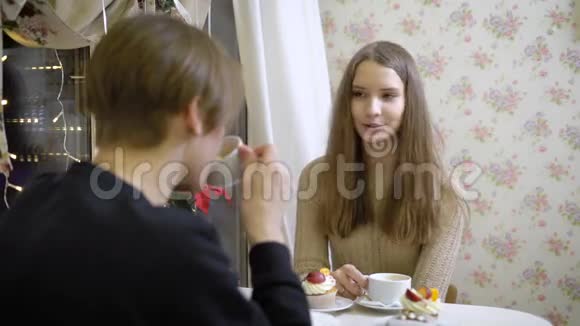 不错的一对年轻人在咖啡馆聊天女孩微笑着看着她的男朋友她喝咖啡温暖的手美丽美丽视频的预览图