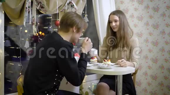 不错的一对年轻人在咖啡馆聊天女孩微笑着看着她的男朋友她喝咖啡温暖的手美丽美丽视频的预览图