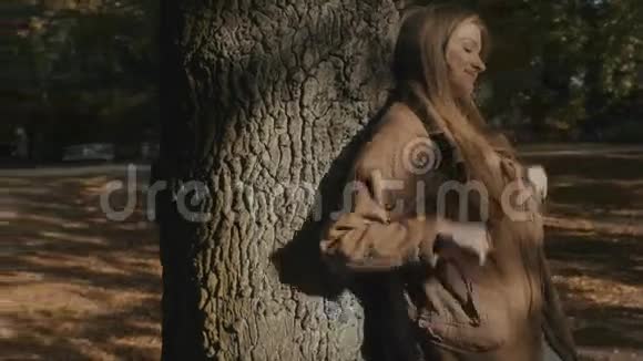 一个年轻的金发女人在秋天的森林里的一棵树下放松视频的预览图