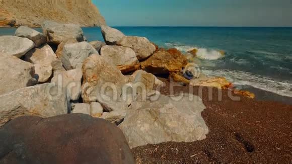 地中海火山海滩的倾斜镜头红沙和冲浪撞击岩石视频的预览图