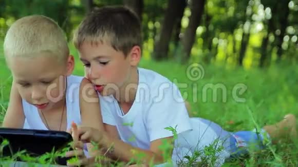 两个穿白衣服的男孩躺在草地上视频的预览图
