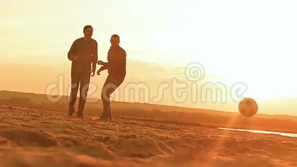 日落时分在海滩上男人们抛出一个足球慢动作视频视频的预览图