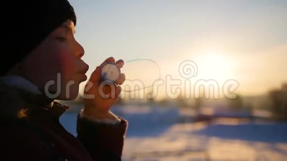 冬天的日落男孩在公园里吹肥皂泡视频的预览图